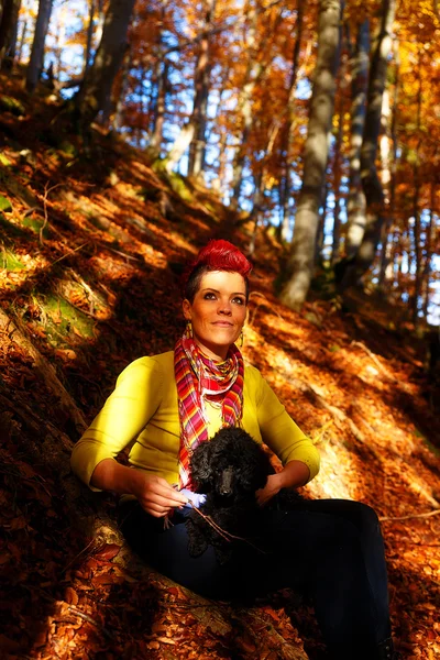 Jolie fille avec chien noir souriant et étreignant à la forêt d'automne en plein air . — Photo