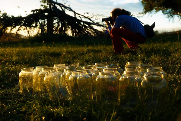 Üres palackozó sor tégelyek, a naplemente csodálatos esti fényben. a fotós a háttérben. — Stock Fotó