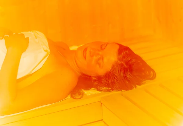 Young woman with brown hair enjoying sauna wellness. — Stock Photo, Image