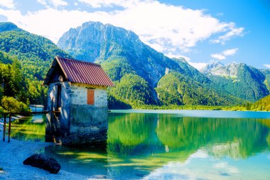 çarpıcı dağ manzarası ile çevrili güzel bir göle küçük binasında.