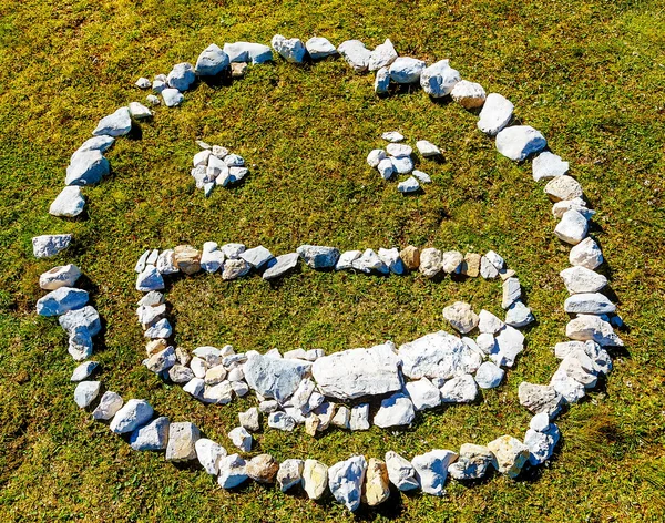 smiling face icon made of pebble stones on mountain meadow