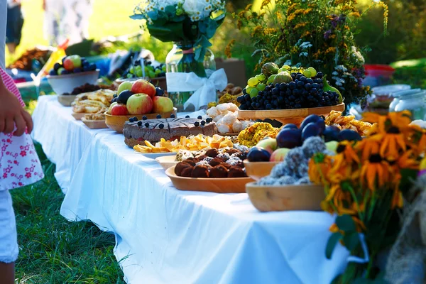 Mahlzeiten auf dem Tisch des Überflusses als Teil einer natürlichen Hochzeitszeremonie in der Natur. — Stockfoto