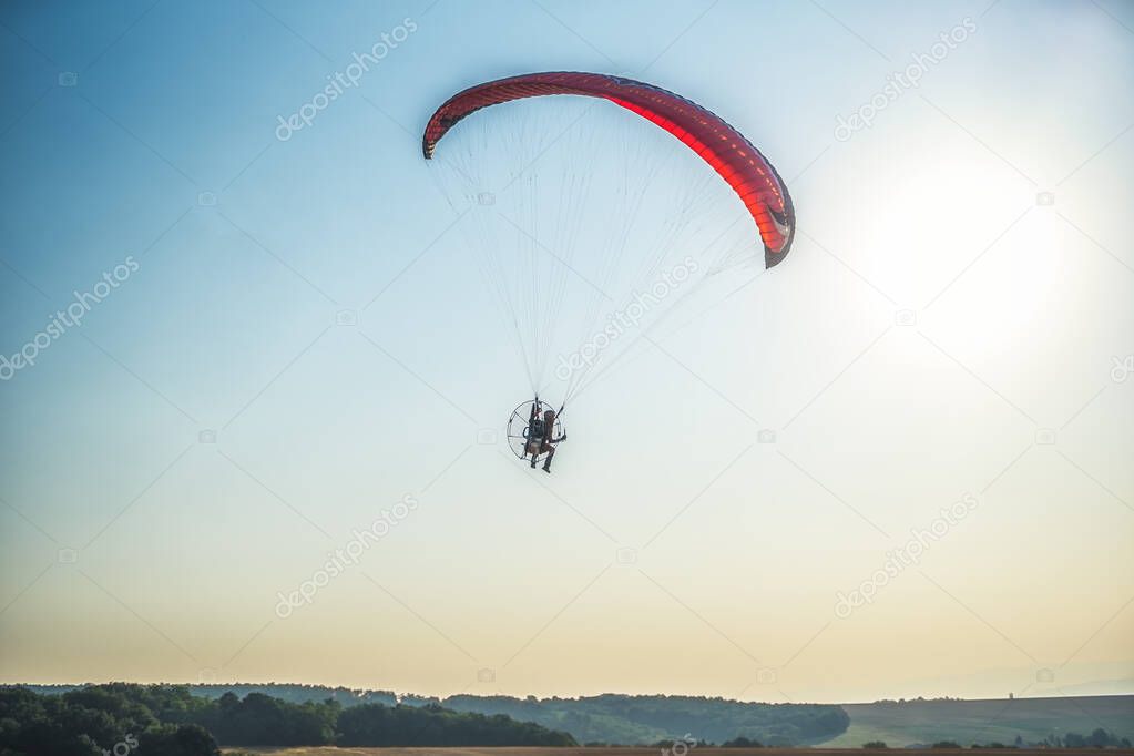 Paraglider in the air, beautiful blue sky in the background.