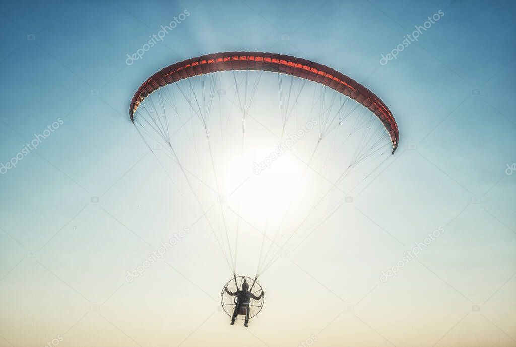 Paraglider in the air, beautiful blue sky in the background.