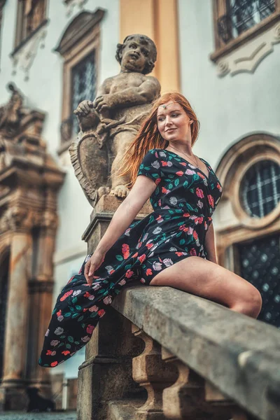 Beautiful fashion model near an angel statue. — Stock Photo, Image