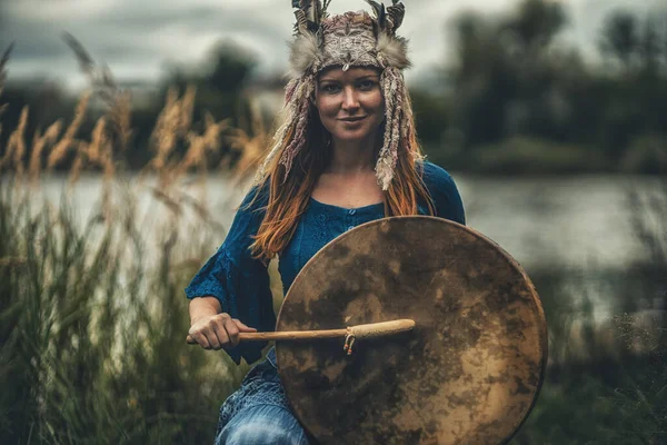 Mooi sjamanistisch meisje spelen op sjamaan frame drum in de natuur. — Stockfoto