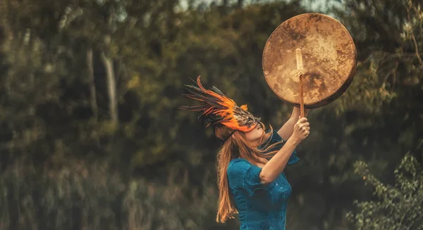 Hermosa chica chamánica jugando en tambor marco chamán en la naturaleza. — Foto de Stock