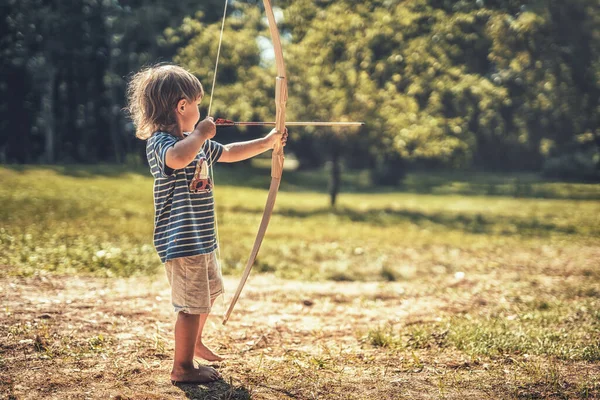 Young boy shoots with a wooden bow. — Stock Photo, Image