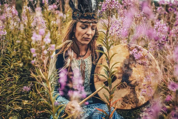 Hermosa chica chamánica jugando en tambor marco chamán en la naturaleza. — Foto de Stock