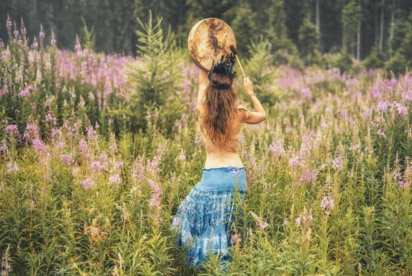 Mooi sjamanistisch meisje spelen op sjamaan frame drum in de natuur. — Stockfoto