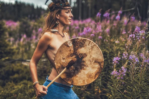 Hermosa chica chamánica jugando en tambor marco chamán en la naturaleza. — Foto de Stock