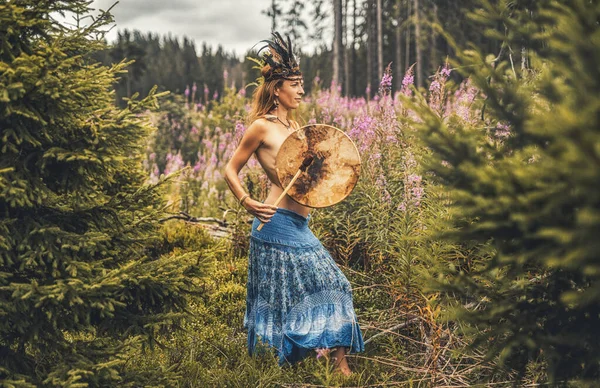 Schönes schamanisches Mädchen, das auf einer schamanischen Rahmentrommel in der Natur spielt. — Stockfoto