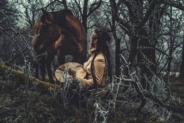 Şaman kadın atıyla kışın manzarada.