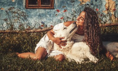 kadın ve köpek gün batımında çayırda.