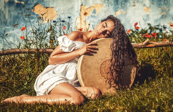 Beautiful shamanic girl playing on shaman frame drum in the nature. — Stock Photo, Image