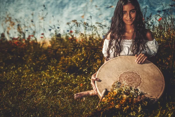 Beautiful shamanic girl playing on shaman frame drum in the nature. — Stock Photo, Image