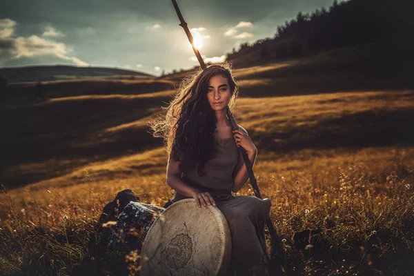 Mooi sjamanistisch meisje spelen op sjamaan frame drum in de natuur. — Stockfoto