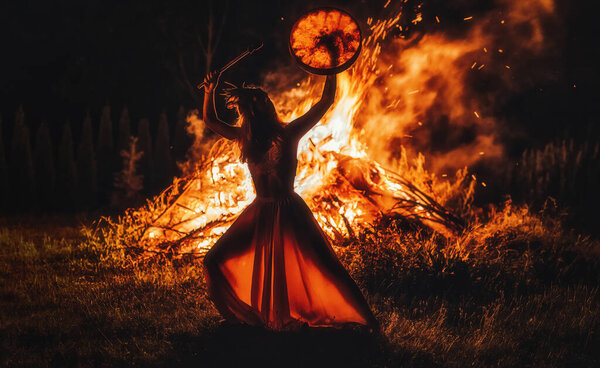 beautiful shamanic girl playing on shaman frame drum in the nature.