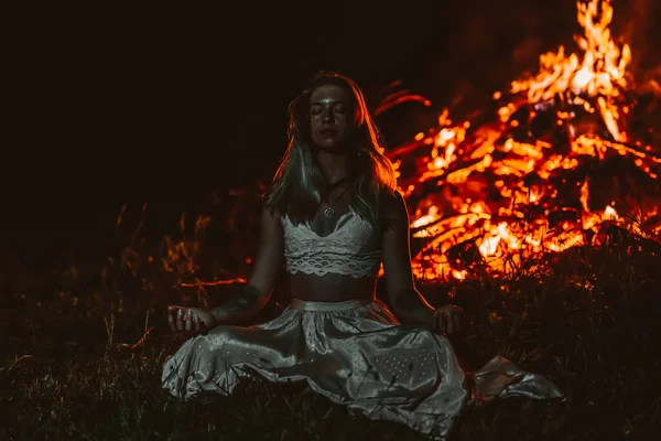 Hermosa mujer meditando junto al fuego. — Foto de Stock