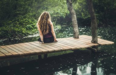 Genç bayan iskelede oturuyor..