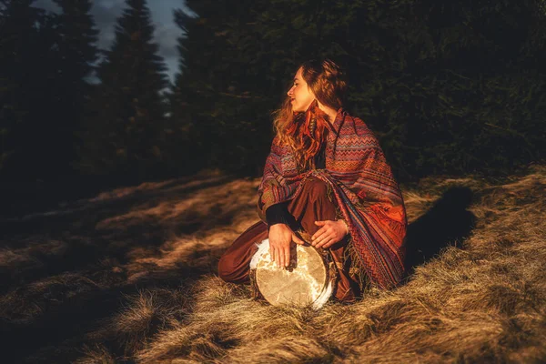 Hermosa chica chamánica tocando el tambor en la naturaleza. — Foto de Stock