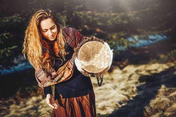 Vacker shamansk flicka spelar på trumma i naturen. — Stockfoto