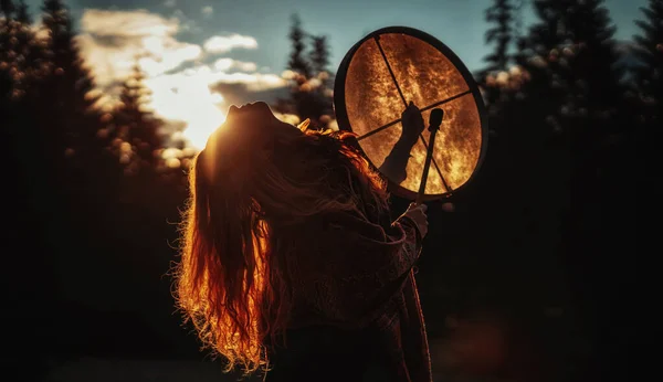 Mooi sjamanistisch meisje spelen op sjamaan frame drum in de natuur. — Stockfoto