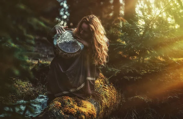 Bella sciamanica ragazza a suonare il tamburo nella natura. — Foto Stock