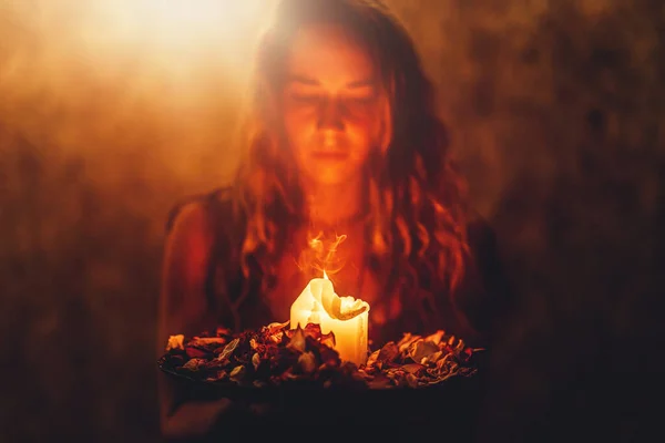 여자 손에 양초, 장미 빛 윤활유가 담긴 그릇 위에서 의식을 거행하는 촛불. — 스톡 사진
