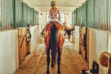 Ahırda ata binen bir kız.