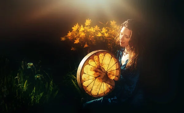 Beautiful shamanic girl playing on shaman frame drum in the nature. — Stock Photo, Image