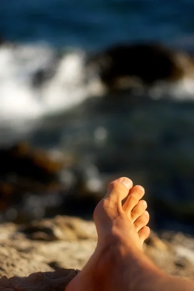 Férfi láb pihentető nyaralás a tengerparton vagy a tó a tenger ater, a háttérben — Stock Fotó