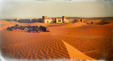 Gün ışığından yararlanma koşulları içinde yakalanan bir antik Arapça kale yakınında parlayan dunes üzerinde bir Arap kampı renkli çadır Fas bir çöl sahne yaymak