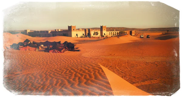Μια μαροκινή έρημο τοπίο με ένα αραβικό στρατόπεδο της πολύχρωμα σκηνές στο λαμπερό αμμόλοφους, κοντά σε ένα αρχαίο αραβικό φρούριο — Φωτογραφία Αρχείου