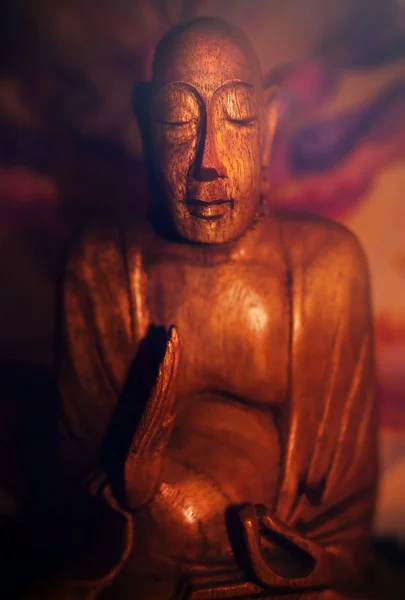 Una estatua de madera de Buda meditando, sobre fondo abstracto colorido — Foto de Stock