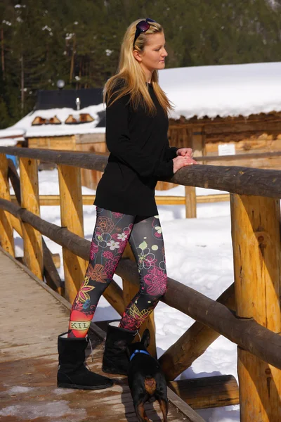 Une belle jeune femme blonde, dans un paysage hivernal enneigé, avec chien — Photo