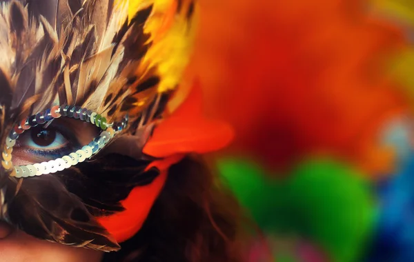 Jeune femme avec un masque de carnaval de plumes coloré sur lumineux — Photo