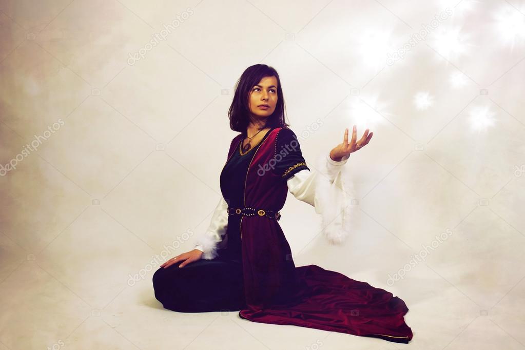 Beautiful young woman posing in historical velvet dress making a dramatic gesture, on a white background