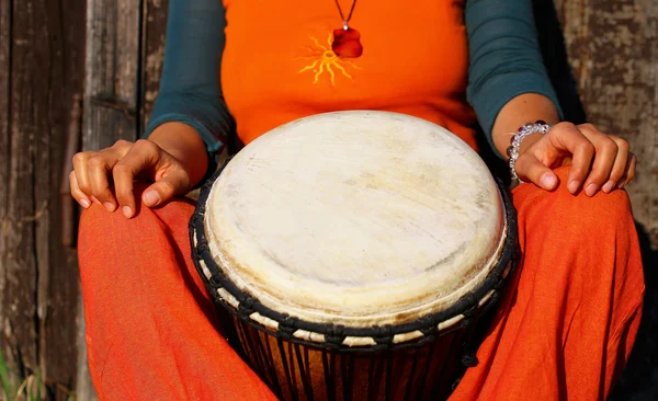 Jonge dame drummer met haar djembe trommel op rustieke houten deur achtergrond. — Stockfoto