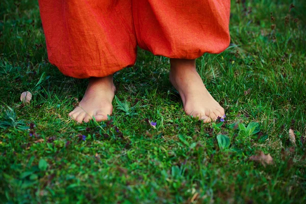 Mujer pies en la hierba con pantalones naranja —  Fotos de Stock