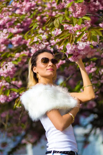 Beautiful Girl with flowers, Spring Magic. Sakura pink flowers. With glamour white fur, and sunglasses — Stock Photo, Image