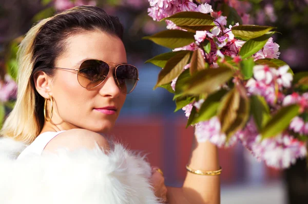 Beautiful Girl with flowers, Spring Magic. Sakura pink flowers. With glamour white fur, and sunglasses — Stock Photo, Image