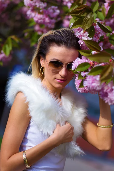 Beautiful Girl with flowers, Spring Magic. Sakura pink flowers. With glamour white fur, and sunglasses — Stock Photo, Image