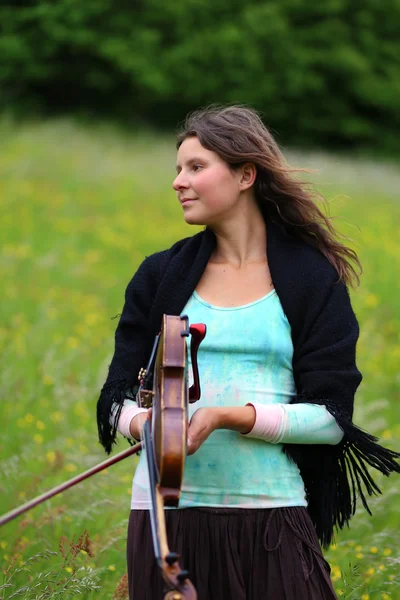 Violist op een weiland vol met bloemen, jong meisje spelen muziekinstrument — Stockfoto