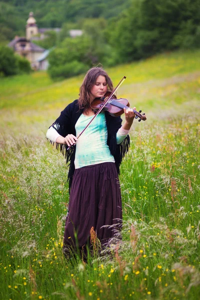 Violist op een weiland vol met bloemen, jong meisje spelen muziekinstrument — Stockfoto