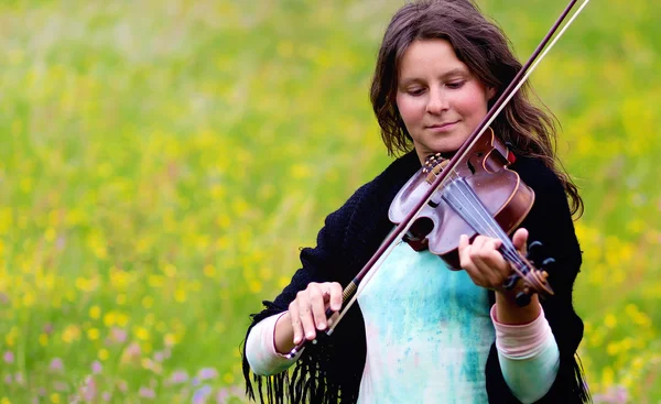 Violist op een weiland vol met bloemen, jong meisje spelen muziekinstrument — Stockfoto