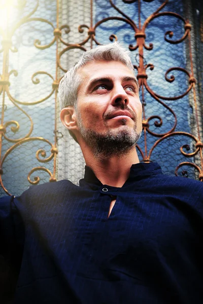 Portrait of a sexy man in wolf  fur and ornamental medieval window on background. — Stock Photo, Image