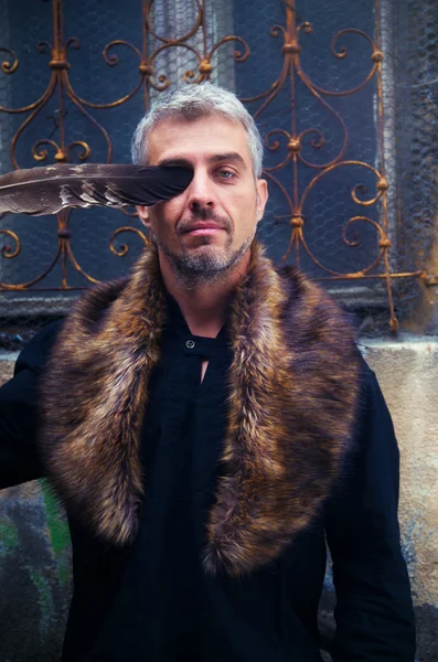 Portrait of a sexy man and eagle feathers, and ornamental medieval window on background. — Stock Photo, Image