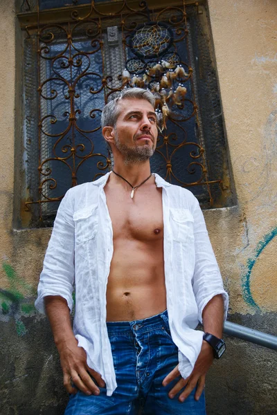 Sexy modelo masculino retrato de moda caliente en jeans elegantes y camisa con cuerpo muscular posando. Y atrapasueños . —  Fotos de Stock