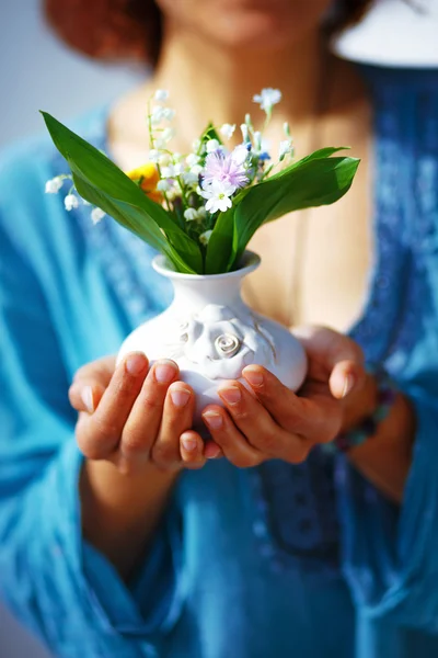 Mulher segurando buquê de flor em vaso. Fundo de roupa azul — Fotografia de Stock